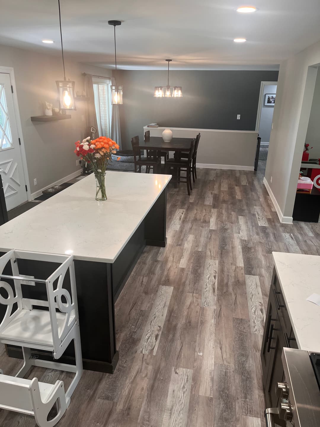 Modern kitchen with a large island, dining area, and floral centerpiece. Bright and spacious design.