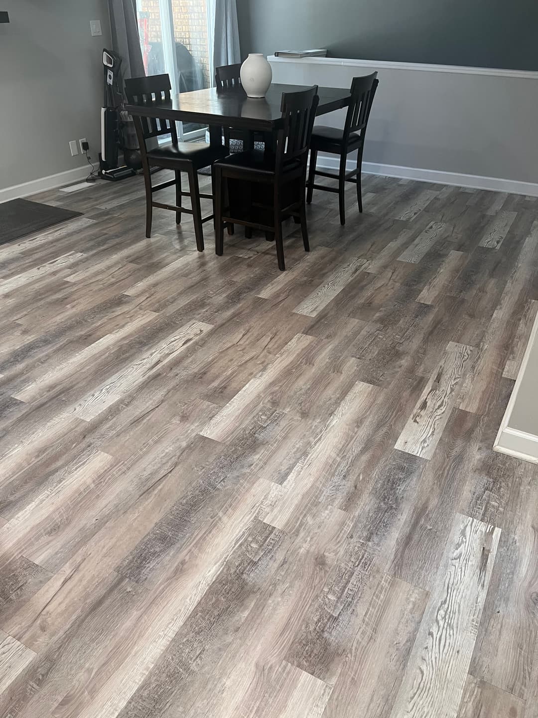 Modern dining area with a wooden table, chairs, and stylish flooring. Bright and inviting space.