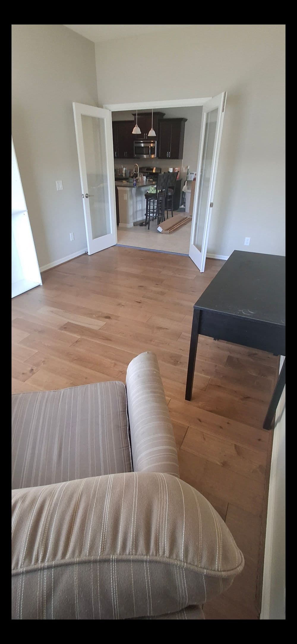 Modern living room with hardwood floors, showcasing an open kitchen and a cozy chair.