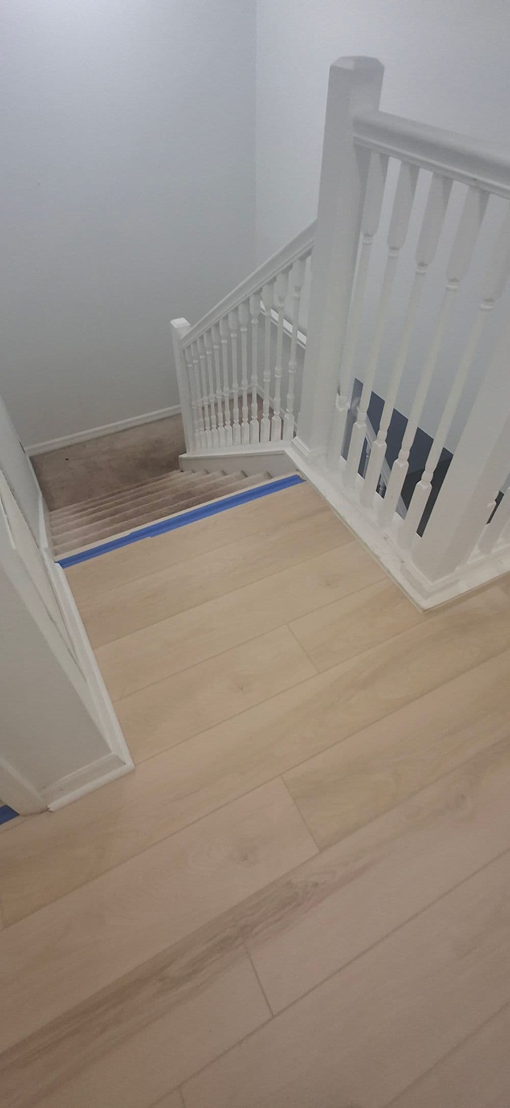Modern staircase with white railings and light hardwood flooring, emphasizing interior design.