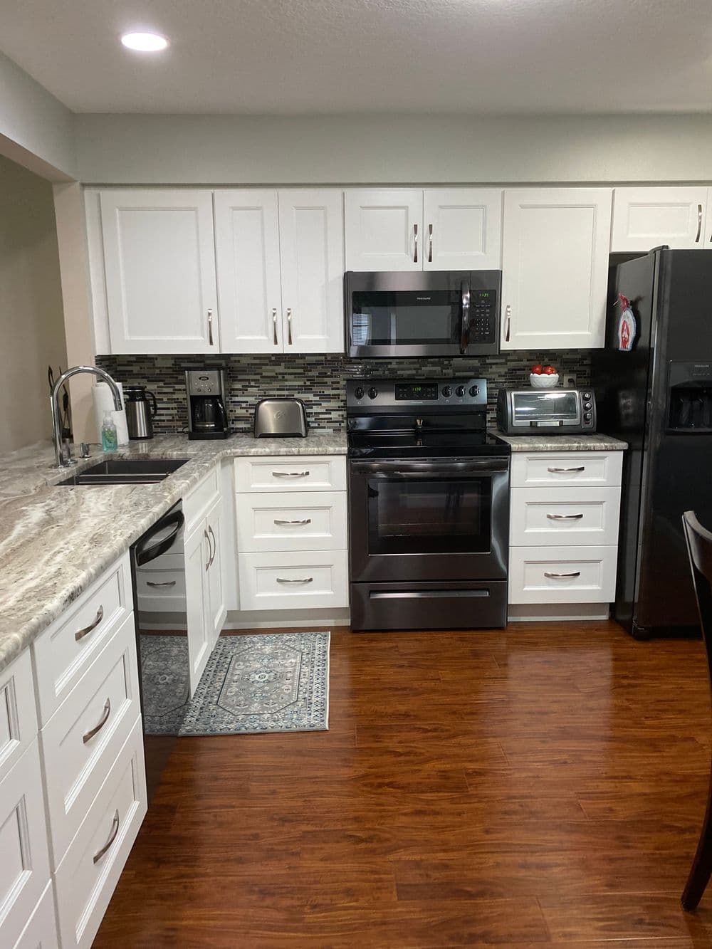 Modern kitchen featuring stainless steel appliances, white cabinetry, and a marble countertop.