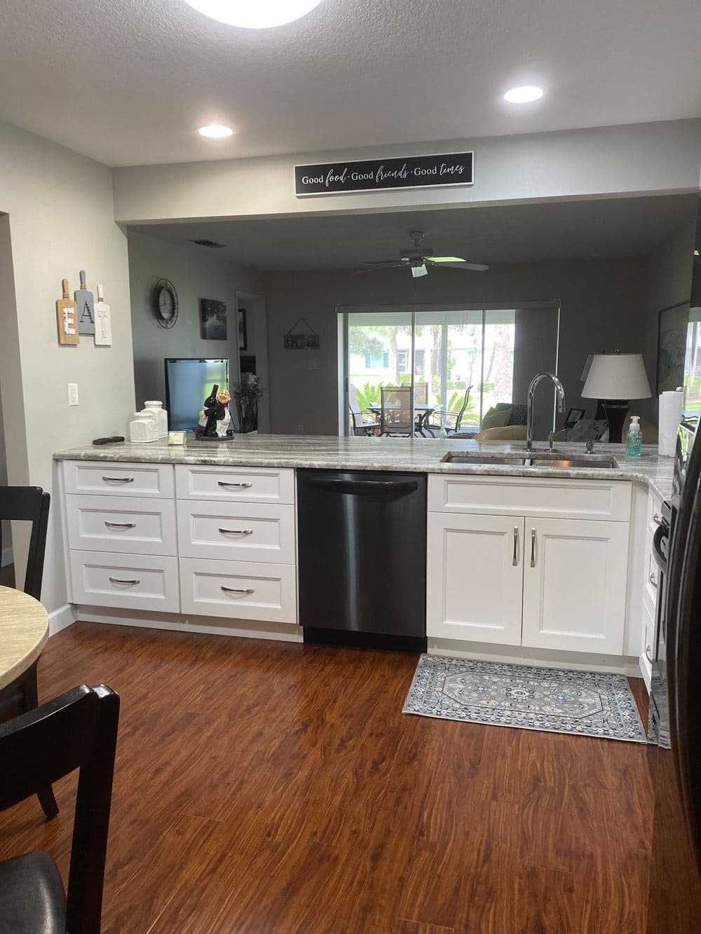 Modern kitchen with white cabinets, granite countertop, and black dishwasher in a bright space.